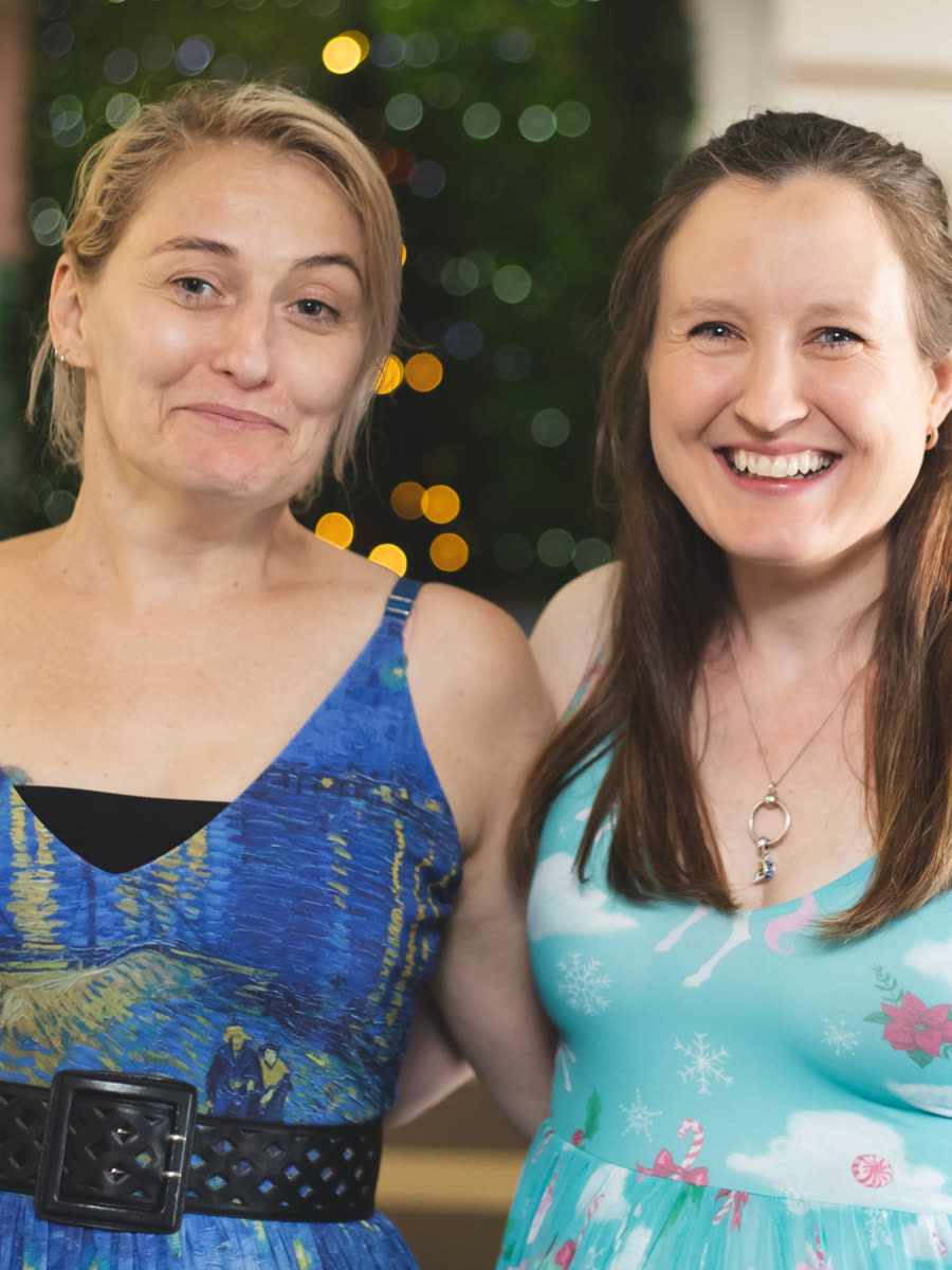 Two friends smiling at the Reach Supports Christmas party